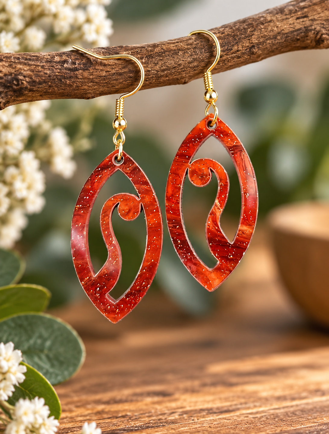 Red glitter acrylic statement earrings with swirl cut-out design and gold-tone hooks, laser cut and made in New Zealand by Dopey Dog NZ.